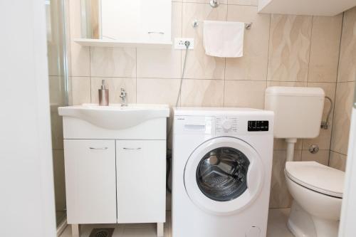 ein Badezimmer mit einer Waschmaschine und einem Waschbecken in der Unterkunft Apartments Maja in Rogoznica