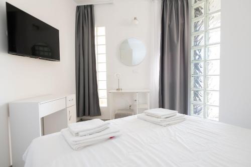 a white bedroom with a bed and a tv at Apartments Maja in Rogoznica