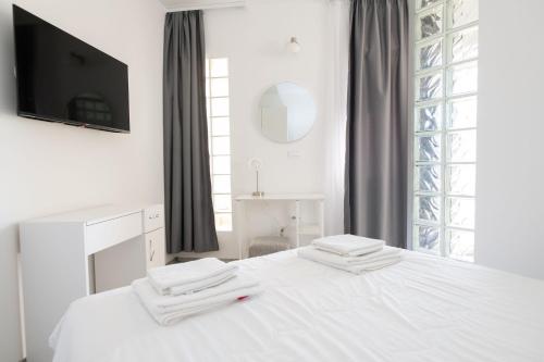 ein weißes Schlafzimmer mit einem Bett und einem TV in der Unterkunft Apartments Maja in Rogoznica