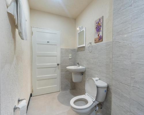 a white bathroom with a toilet and a sink at Kahili Apartments in The Lime