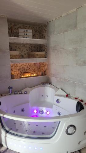 a white bath tub with pink lights in a bathroom at Au Fil De l' Eau in Aurec-sur-Loire