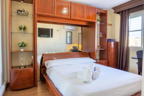 Apartment Aconte Malaga في مالقة: غرفة نوم بسرير من الشراشف البيضاء والخزائن الخشبية