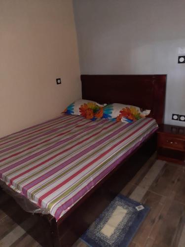 a bed with a wooden headboard in a bedroom at Résidence kenzaina in Ouagadougou