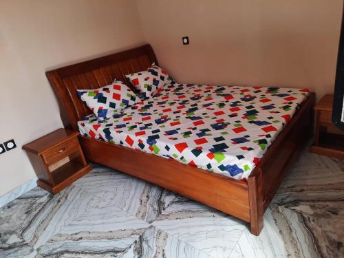 a bedroom with a wooden bed with a colorful comforter at Résidence kenzaina in Ouagadougou