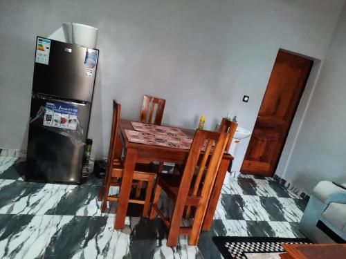 a kitchen with a table and chairs and a refrigerator at Résidence kenzaina in Ouagadougou