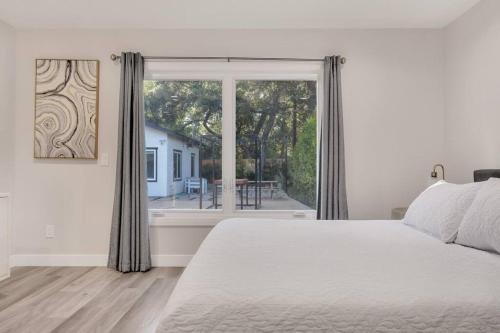 een slaapkamer met een wit bed en een groot raam bij Modern home near colleges in Claremont