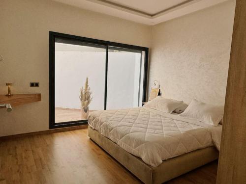 a bedroom with a large bed and a large window at Cozy Appart central à terrasse in Casablanca