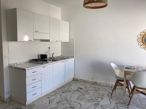 - une cuisine blanche avec une table et des placards blancs dans l'établissement Studio vue mer, 10 min de Monaco !, à Roquebrune-Cap-Martin