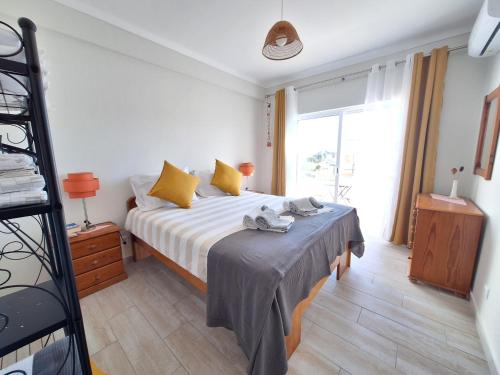 a bedroom with a bed with yellow pillows and a window at AREIAS SOL in Albufeira