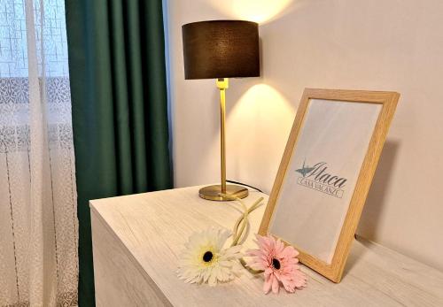 a table with a mirror and a lamp and flowers on it at Itaca in Lido di Fermo