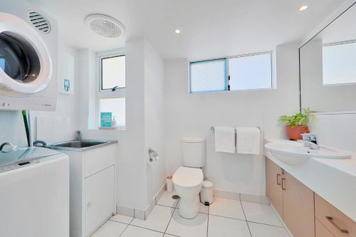 a white bathroom with a toilet and a sink at Ohana Vibe Bargara in Bargara