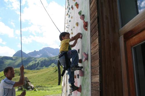 a young boy is climbing a climbing wall at Hotel Adler in Warth am Arlberg