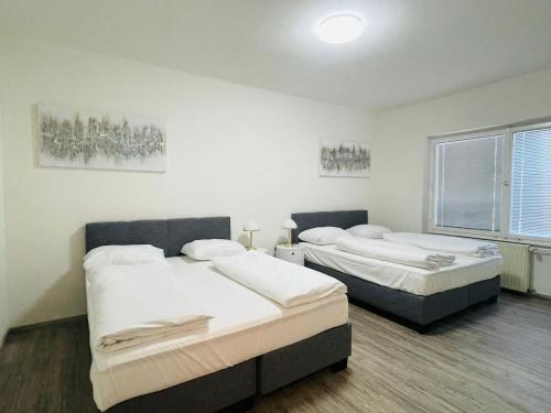 Dos camas en una habitación con paredes blancas. en Evido City Apartment, en Salzburgo