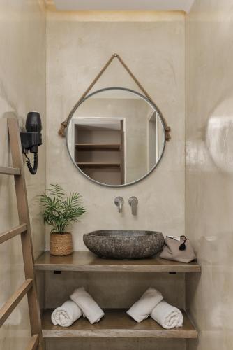 a bathroom with a stone sink and a mirror at Scarabeo Suites & Villas Parga in Parga