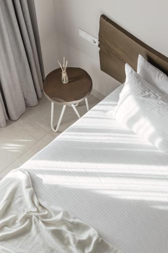 a bed with a table next to a bed with white sheets at Scarabeo Suites & Villas Parga in Parga