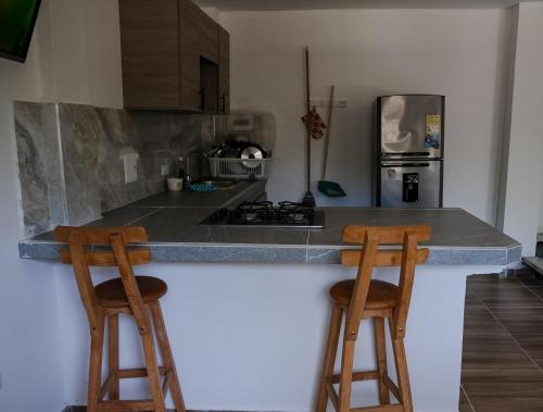 a kitchen with two wooden stools at a counter at Cabañas en San Antero Bambumar2 in San Antero