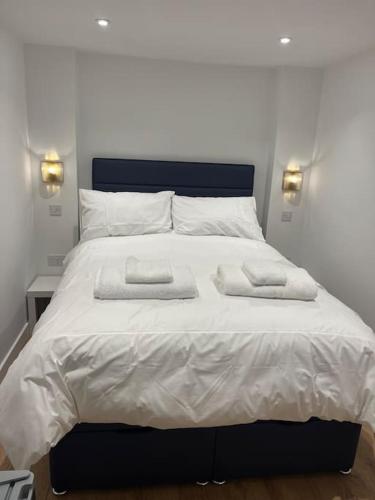 a large white bed with two towels on it at Novanik Studio Apartment in Milton Keynes