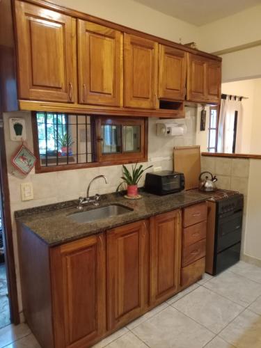 a kitchen with wooden cabinets and a sink at Casa con excelente ubicacion in Posadas