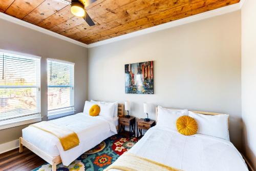 2 camas en un dormitorio con paredes blancas y techos de madera en The Yellow Door Bungalow, en San Antonio