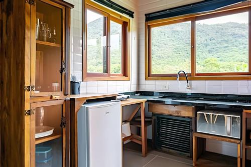 a kitchen with a sink and some windows at Cabanas aconchegantes. Desfrute da natureza e praia in Florianópolis