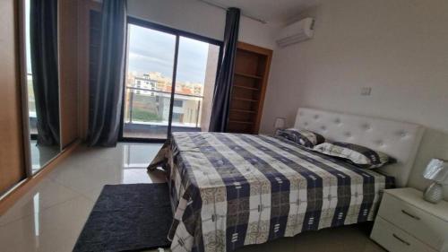 ein Schlafzimmer mit einem Bett und einem großen Fenster in der Unterkunft Aparthouse EdHel T2 in Praia