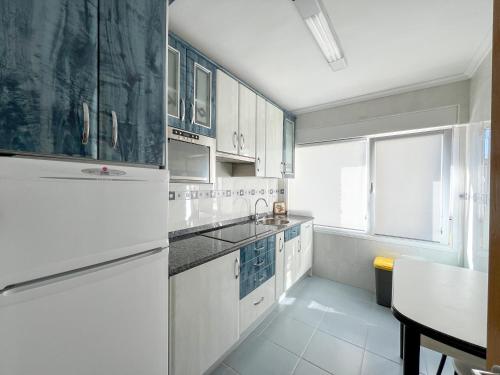 uma cozinha com armários brancos e um frigorífico branco em Apartamento en Costa de Cantabria, Laredo em Laredo