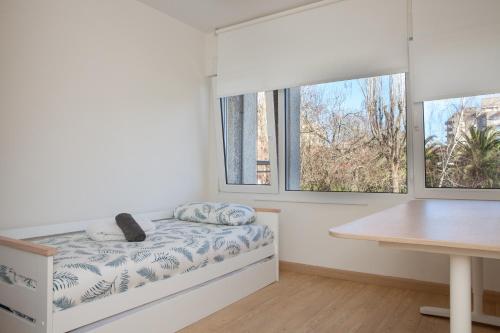 a bedroom with a bed with a desk and two windows at Apartamento en Costa de Cantabria, Laredo in Laredo