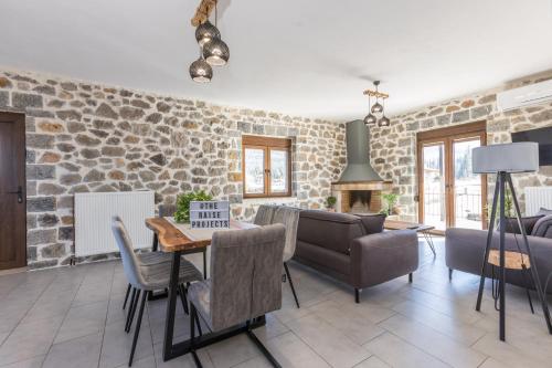 a living room with a table and a stone wall at Raise Polydrosos Alpine Escape in Polydrossos