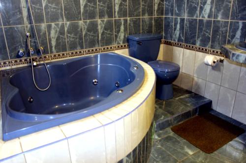 y baño con bañera azul y aseo. en Gran Hotel Alturas, en Huaraz
