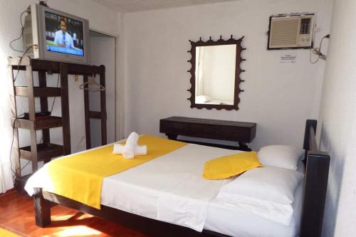 ein Schlafzimmer mit einem Bett mit gelber Decke und einem Spiegel in der Unterkunft Torre del Sol in Villavicencio
