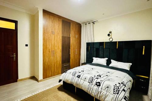 - une chambre avec un grand lit et une couette noire et blanche dans l'établissement BlackOak Luxury Home B06 1BR Kyanja, à Kampala