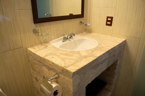 uma casa de banho com um lavatório em mármore e um dispensador de papel higiénico em Hotel Boutique Sacramento em Bernal