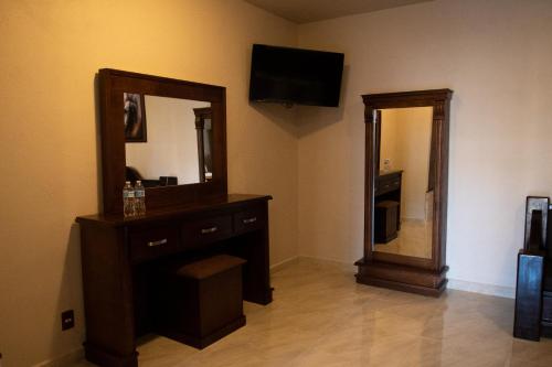 a bathroom with a dresser and a mirror and a television at Hotel Boutique Sacramento in Bernal