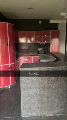 a kitchen with red cabinets and a black counter top at منتجع السرايا السياحي in Al Qā‘id