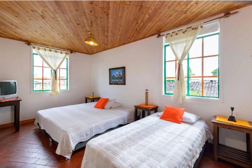 two beds in a room with two windows at Hotel Veraneras del Quindío in Pueblo Tapao