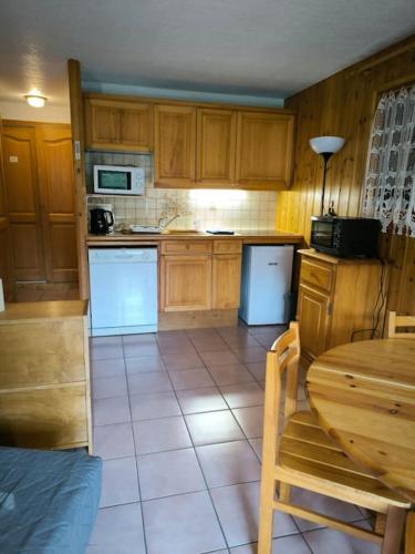 - une cuisine avec des placards en bois, une table, une table et des chaises dans l'établissement Appartement à 50m des remontées, à Saint-Gervais-les-Bains