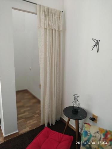a living room with a curtain and a table at Pousada Tia Rosi com suites independente 100 mts da praia c ar, energia solar e atendimento vip in Rio das Ostras
