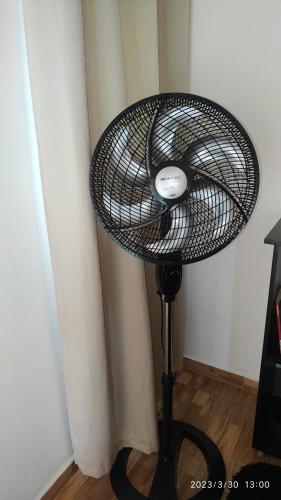 a fan on a stand next to a wall at Pousada Tia Rosi com suites independente 100 mts da praia c ar, energia solar e atendimento vip in Rio das Ostras