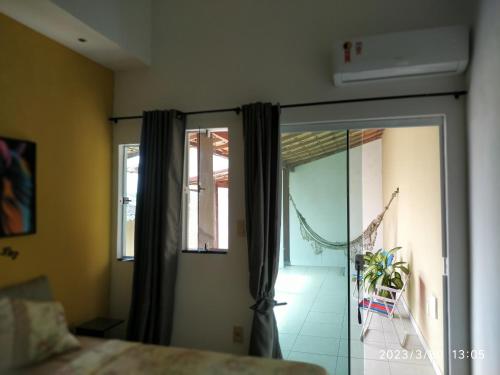 1 dormitorio con 1 cama y puerta corredera de cristal en Tia Rosi tem suite independente 200mts da praia c ar e energia solar c atendimento vip en Rio das Ostras