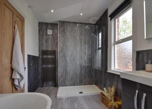 a bathroom with a shower and a tub and a sink at Autumn Loft Wyndale Living Malvern Hills - Free Parking in Great Malvern
