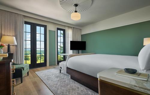 a bedroom with a bed and a desk with a tv at Pendry Natirar 