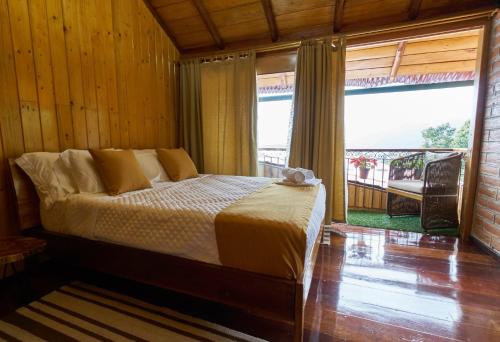 a bedroom with a bed and a large window at Casa de Vista Alta in Mindo