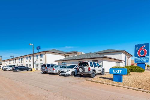 een parkeerplaats met auto's geparkeerd voor een dealer bij Motel 6-Winslow, AZ in Winslow