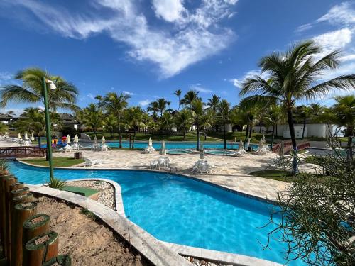 uma piscina no resort com palmeiras em Beach Class Muro Alto Resort - flats e bangalôs em Porto de Galinhas