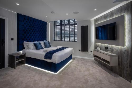 a bedroom with a bed with a blue headboard and a television at The Charleston in Blackpool