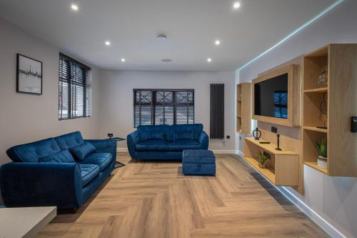 a living room with two blue couches and a tv at The Charleston in Blackpool