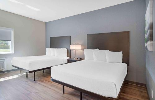two beds in a hotel room with white sheets at Extended Stay America Suites - Baytown in Baytown