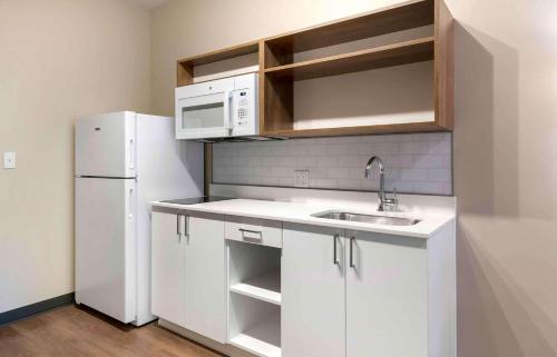 a white kitchen with a sink and a refrigerator at Extended Stay America Suites - Baytown in Baytown