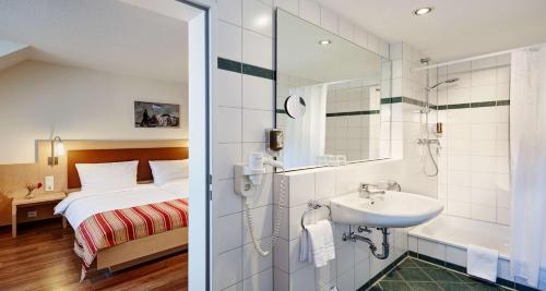 a bathroom with a sink and a bed and a shower at Hotel Imperial Dusseldorf - Sure Collection by BW in Düsseldorf