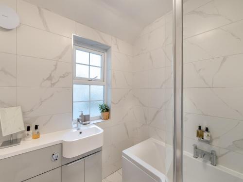 a white bathroom with a sink and a shower at Coral Cottage in Amble